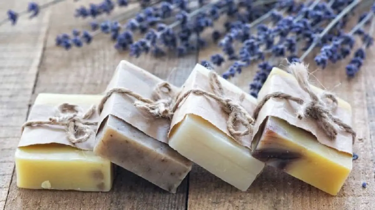 four natural handmade soaps over wooden table with lavender flowers