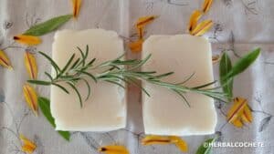 2 white soap bars made with coconut oil, decorated with rosemary and yellow flower petals