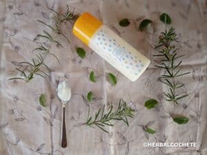 bottle of homemade hair conditioner and spoon with small sample, with green leaves decoration