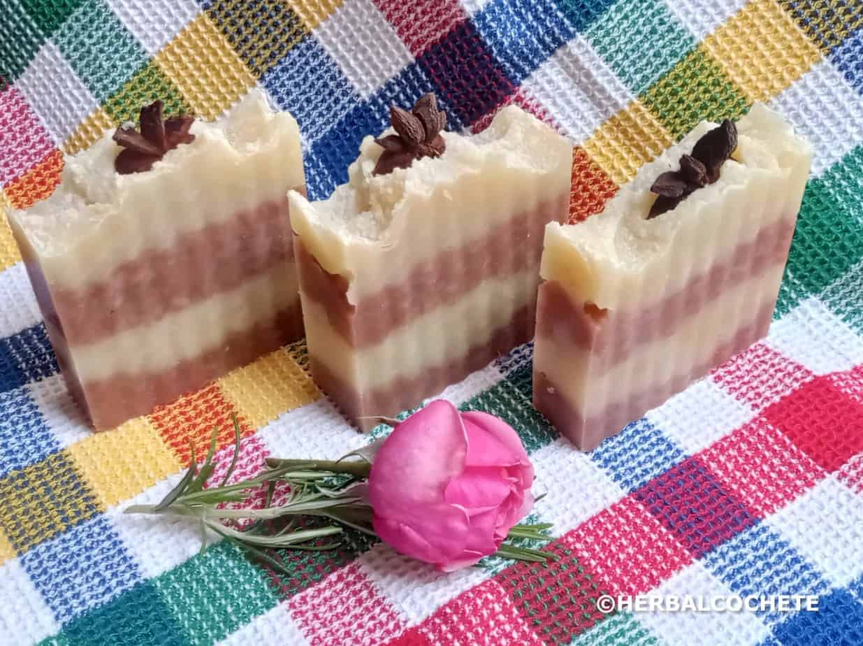3 pretty soap bars with layered red and cream colors with star anis on top and decorated with a rose